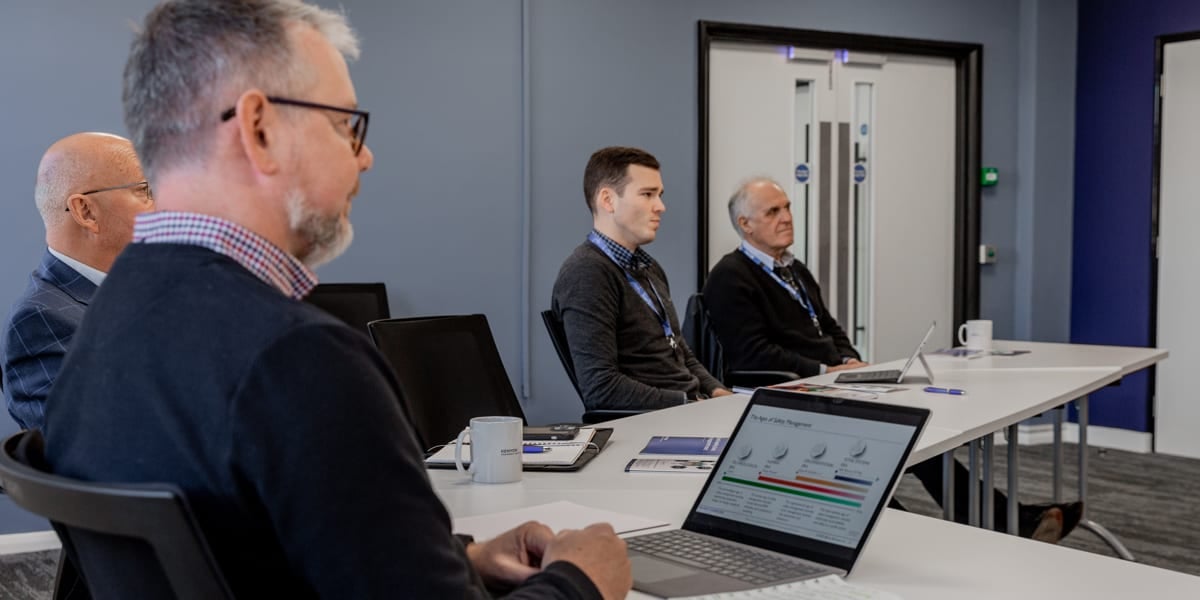 men around a table with laptops