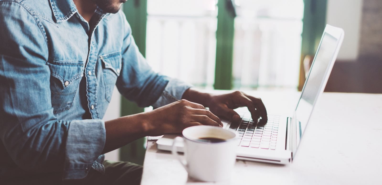 man on his laptop with a coffee their side
