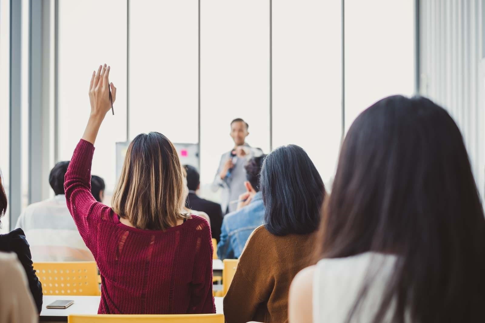 woman with hand up in a meeting